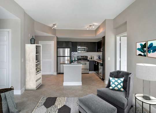 A modern kitchen with a grey chair and a white island.