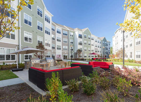 A modern apartment complex with a landscaped courtyard in the foreground.