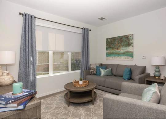 A living room with a grey couch, a coffee table, and a painting on the wall.