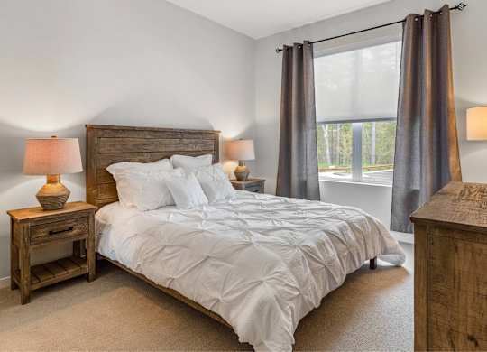 A bedroom with a large bed and two lamps.