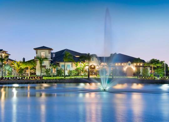 A beautiful fountain in front of a building at dusk.