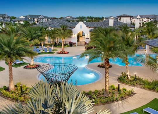 A pool surrounded by palm trees and plants.