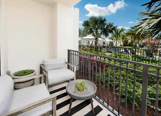 A balcony with a table and chairs overlooking a garden.