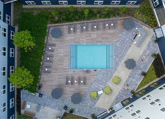 A pool surrounded by a wooden deck and patio furniture.