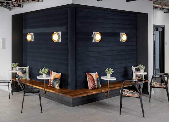 A black booth with four chairs and a table with four vases on it.