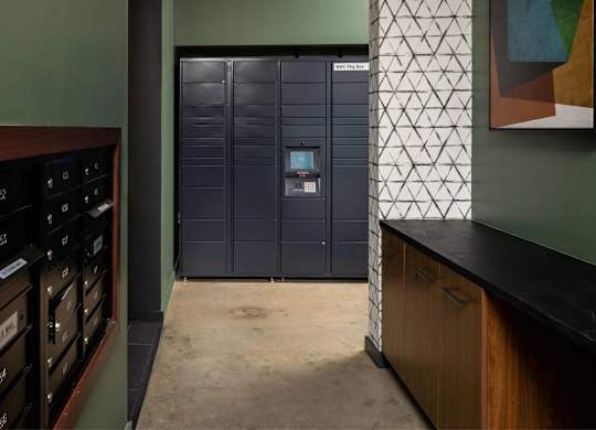 A tall, dark blue metal storage unit with a digital keypad on the door stands in a room with a green wall and a wooden counter.