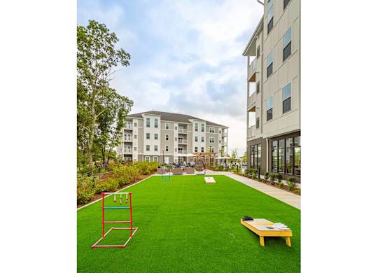 A playground with a swing set and a bench in the middle of a grassy area.