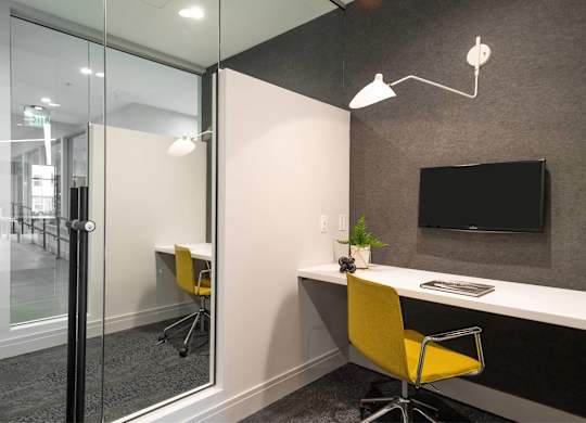 A modern office with a yellow chair and a glass wall.