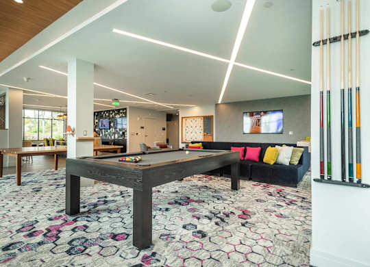 A pool table in a room with a couch and a TV.