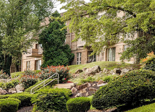 A large house with a green lawn and trees in front.