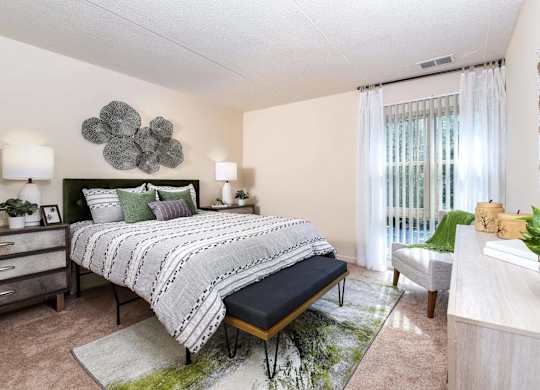 A bedroom with a large bed and a green plant on the side table.