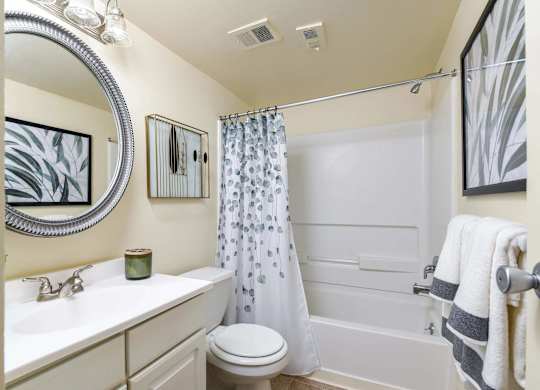 A white bathroom with a toilet, sink, and shower.