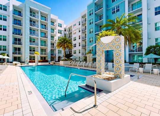 A pool surrounded by a white fence and a building in the background.