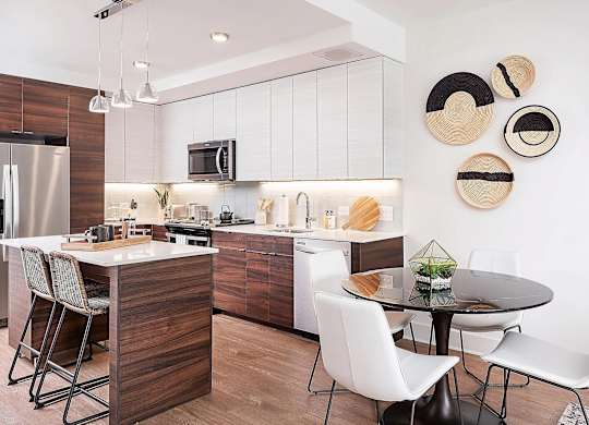 A modern kitchen with a wooden island and white chairs.