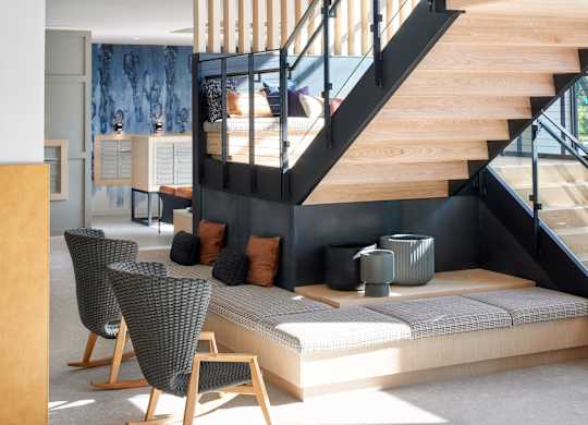 A wooden staircase with a glass balustrade leads to the upper floor of a modern home.