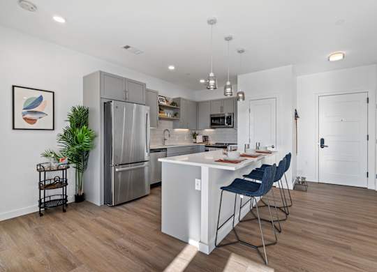 A kitchen with a white island and blue chairs.