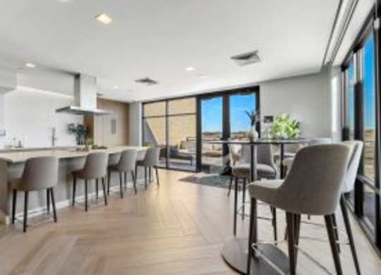 A modern kitchen with a bar area and chairs.
