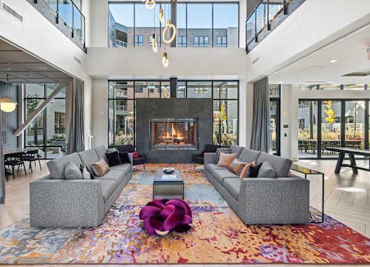 A modern living room with a fireplace and two grey couches.