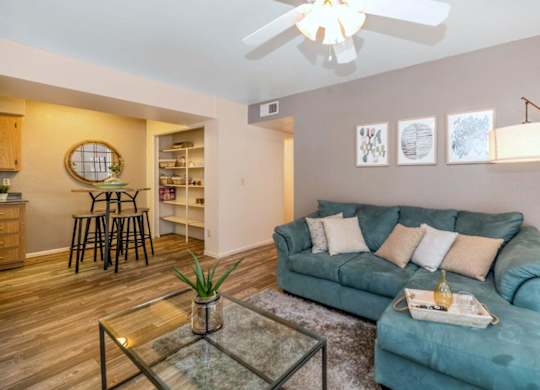 A living room with a blue couch and a glass coffee table at Red Mountain Apartments, Mesa, AZ