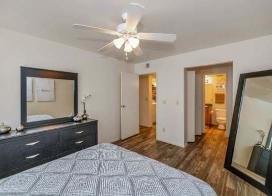 A bedroom with a bed, dresser, mirror, and ceiling fan at Red Mountain Apartments, Mesa, AZ
