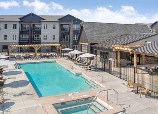 A large outdoor swimming pool surrounded by lounge chairs and umbrellas.