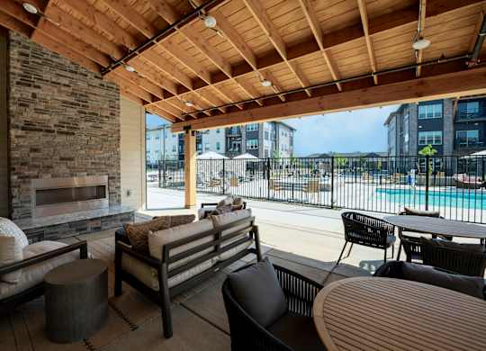 A patio with a stone fireplace and wooden furniture.