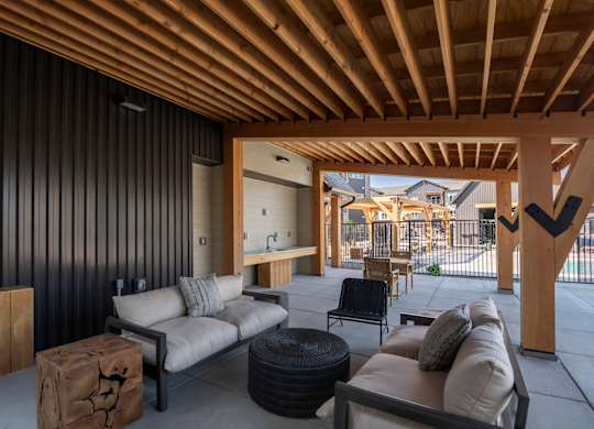 A modern outdoor living space with a wooden ceiling and black wall.