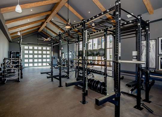 A gym with a variety of equipment including weightlifting machines and dumbbells.