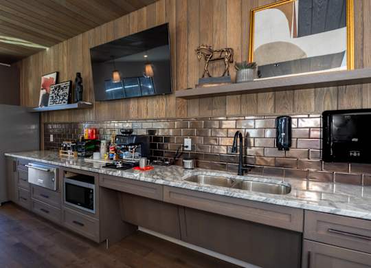 A modern kitchen with a wooden ceiling and a black fridge.