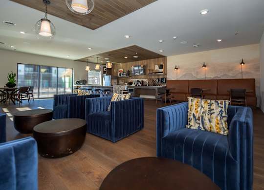 A modern living room with blue velvet chairs and a wooden ceiling.