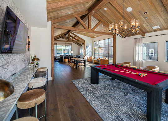A billiard table is in the middle of a room with a wooden ceiling.
