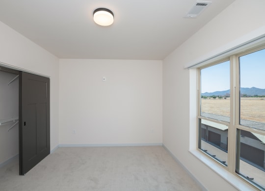 an empty room with a door to a closet and large windows at The Crossings  at Windsong, Prescott Valley, 86314