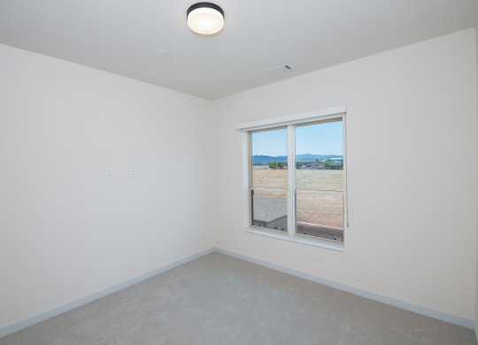 an empty room with a window overlooking a field at The Crossings  at Windsong, Prescott Valley