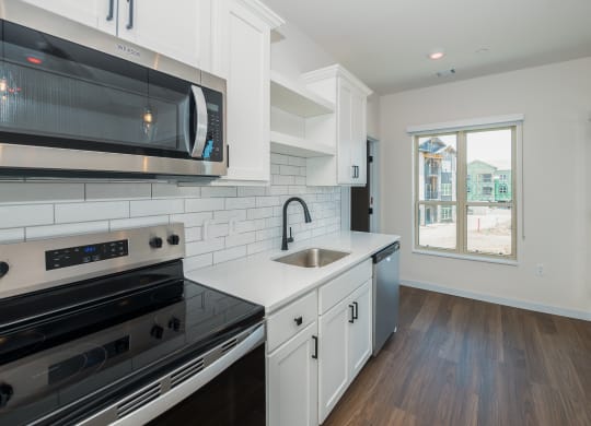a kitchen with white cabinets and black appliances and a window at The Crossings  at Windsong, Arizona