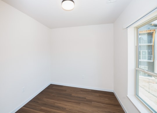 a living room with white walls and wood flooring and two windows at The Crossings  at Windsong, Arizona, 86314