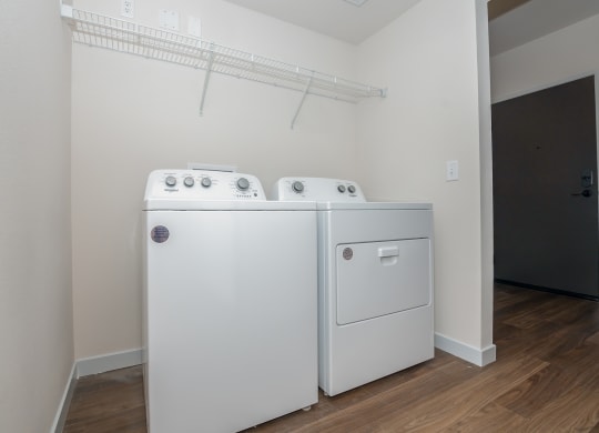 a washer and dryer in a room with a white wall and wood floor at The Crossings  at Windsong, Prescott Valley