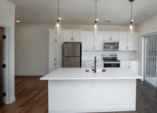 an open kitchen with a large white island and white cabinets at The Crossings  at Windsong, Arizona, 86314