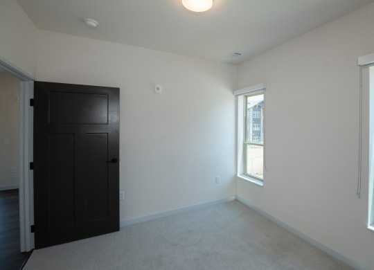 an empty living room with a black door and two windows at The Crossings  at Windsong, Prescott Valley, 86314