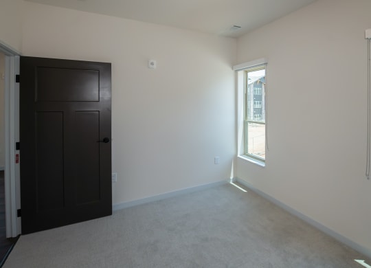 an empty living room with a black door and two windows at The Crossings  at Windsong, Prescott Valley