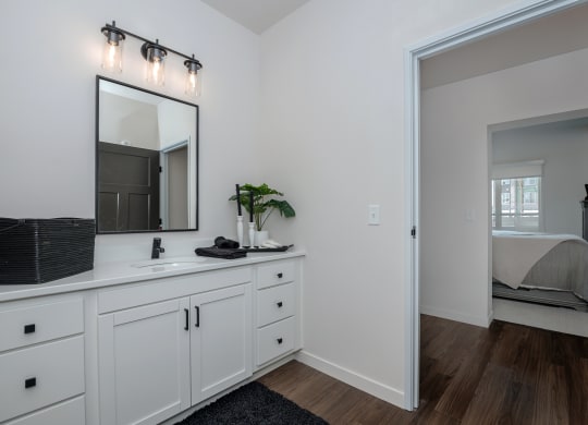 a bathroom with white cabinets and a mirror and a bedroom with a bed at The Crossings  at Windsong, Arizona