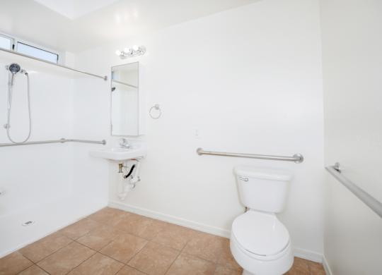 A white toilet in a bathroom with a white sink and a shower.