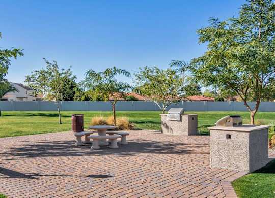 A park with a table and chairs surrounded by trees at Reflections at Red Mountain Apartments, Arizona