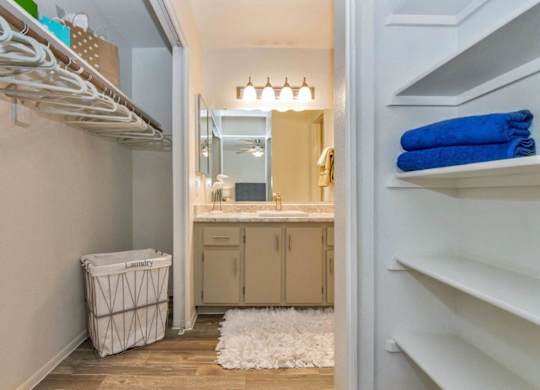 A bathroom with a white laundry basket and a white rug at Reflections at Red Mountain Apartments, Mesa, AZ