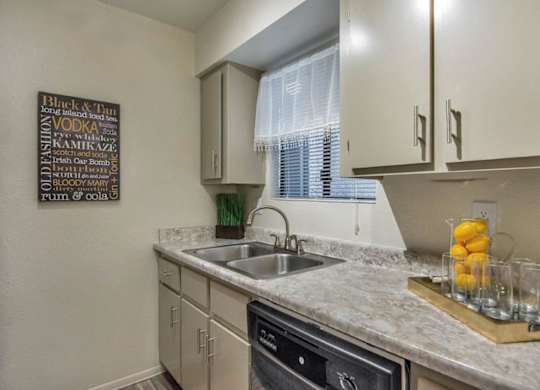 A kitchen with a sink, a window with blinds, and a chalkboard with drink names at Reflections at Red Mountain Apartments, Mesa