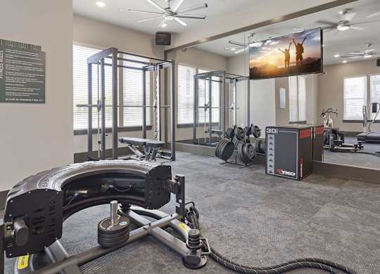 A gym with a weight bench, a fan, and a television.
