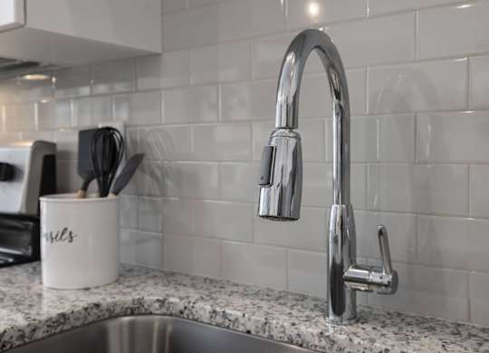 A kitchen sink with a chrome faucet and a mug with the word