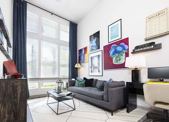 A living room with a grey couch, a coffee table, and a painting on the wall.