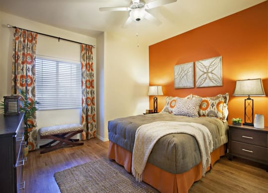 Three-Bedroom Apartments in Goleta, CA- Willow Springs- Bedroom with Ceiling Fan, Orange Accent Wall, and Grey and Orange Comforter set