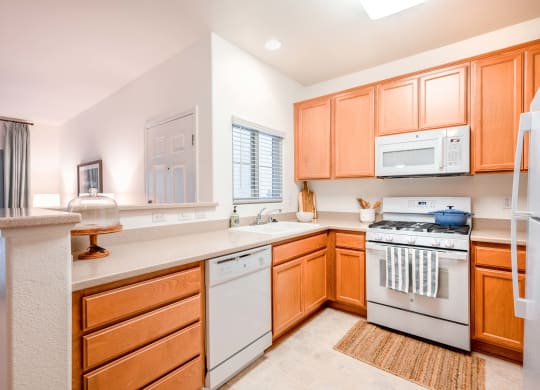 Apartments for Rent in Goleta, CA- Sumida Gardens- Kitchen with White Appliances, Wooden Cabinets, and Spacious Countertops