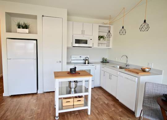 A kitchen with white appliances and wooden floors.